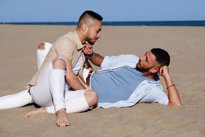 Affectionate gay couple relaxing on beach