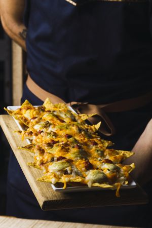 Roasted cheese nachos on plate on wooden stand