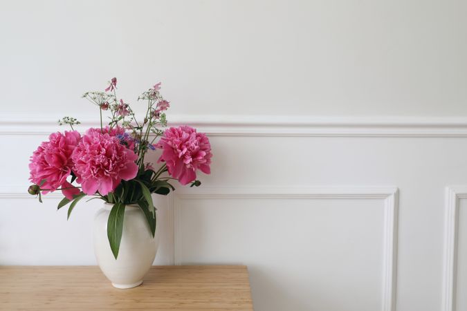 Vase with pink peonies flowers on wooden table