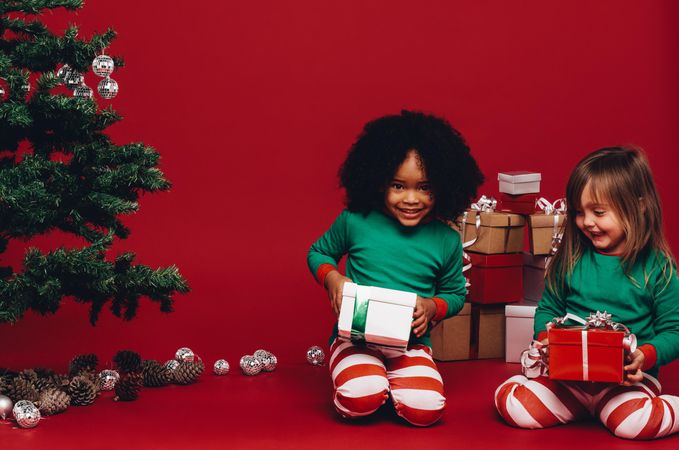 Two little girls dressed in striped pajamas holding gift boxes