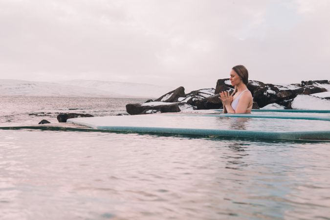 Woman sitting in pool near stones