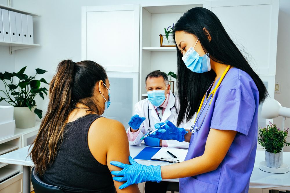 Medical assistant vaccinating patient in doctor’s office