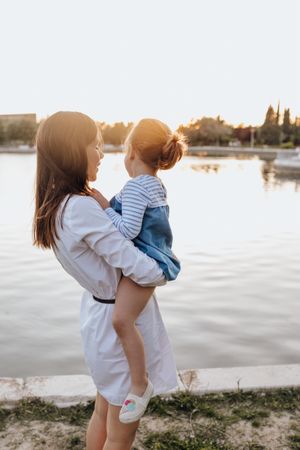 Mother and daughter standing near water