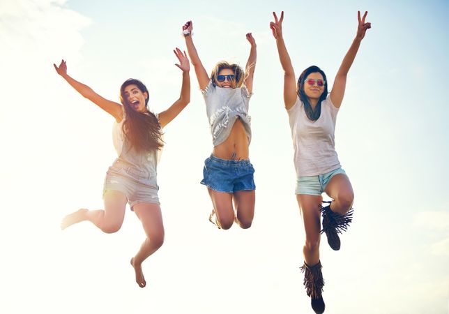 Happy women jumping together on sunny day