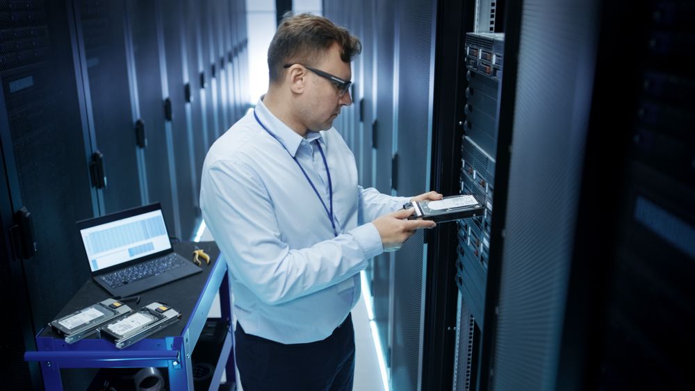 IT Engineer Installing Hard Drives into Working Rack Server.