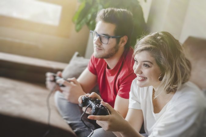 Couple with gamepads playing console