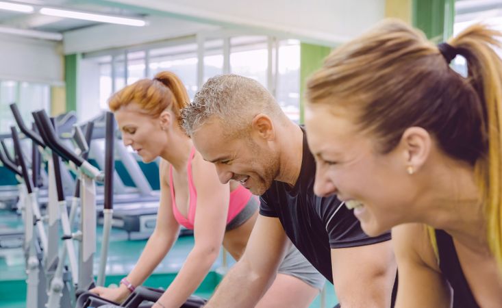 Group of people smiling as they use stationary bikes in gym