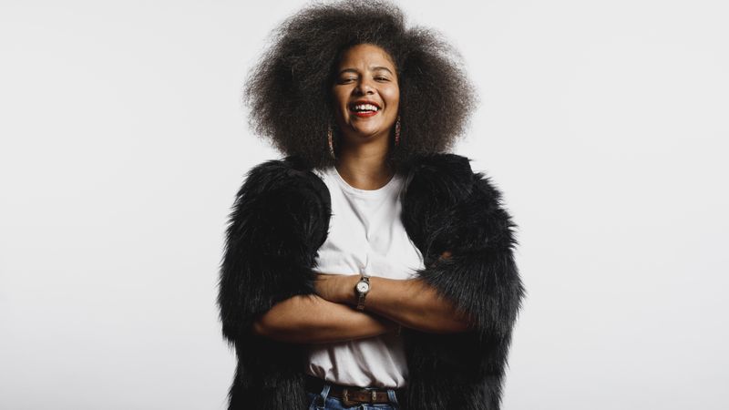 Smiling woman in afro hairstyle standing with arms crossed