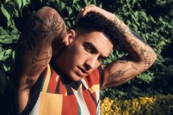 Tattooed male model in garden holding head