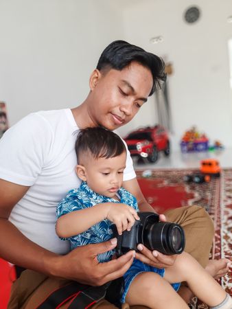 Child and father are playing with a photography camera