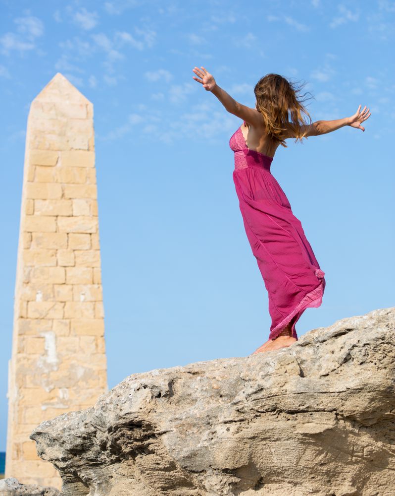 Woman in dress standing near stone monument