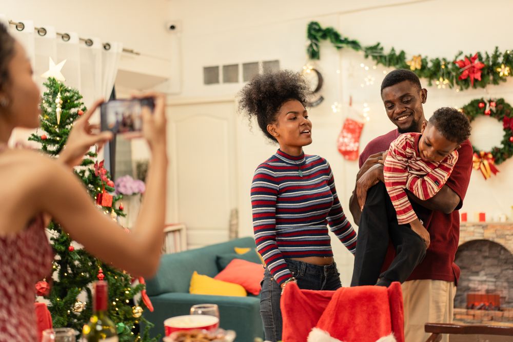 Black woman using smartphone taking picture of a family during Christmas