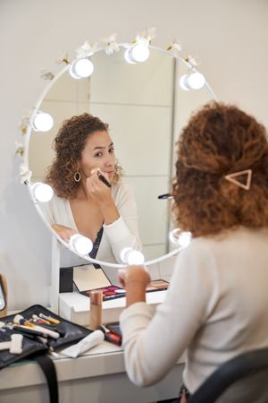 Woman applying makeup near mirror