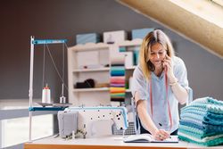 Cheerful seamstress talking on smartphone