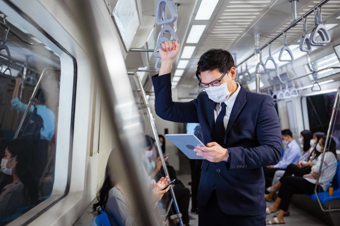 Businessman standing reading tablet in metro car