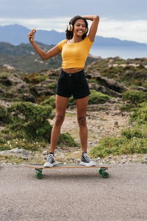 Smiling woman on longboard and taking selfie