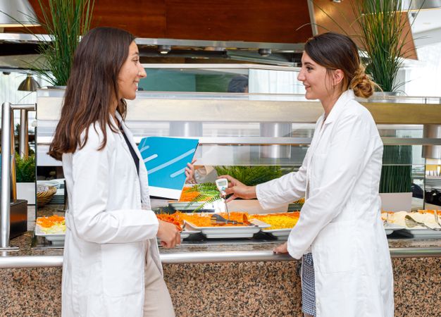 Coworkers having discussion while checking food quality in canteen