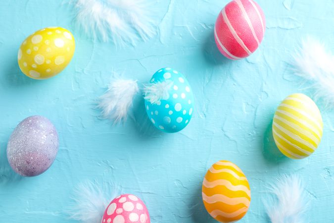 Flat lay composition with Easter eggs and feathers on color background, space for text