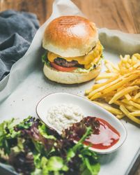 Top view of classic hamburger with fries and cottage cheese at wooden restaurant table