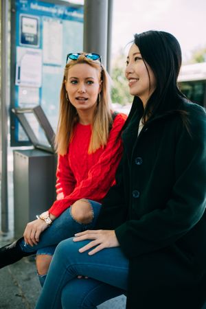 Multiethnic friends sitting on bus stop
