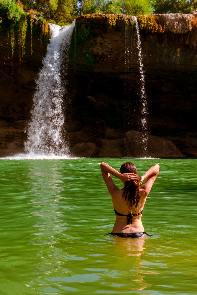 Anonymous female standing near amazing waterfall