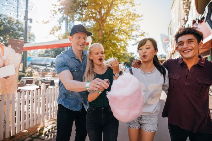 Young man and women sharing cotton candy floss at fairground