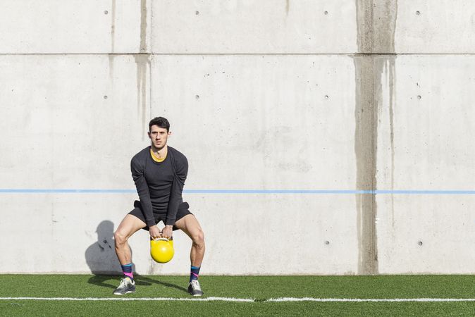 Man training with kettlebell on lawn