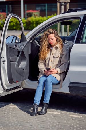 Young woman using smartphone and sitting in car