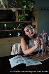 Young biracial woman sculpting clay horse 5r9ol0