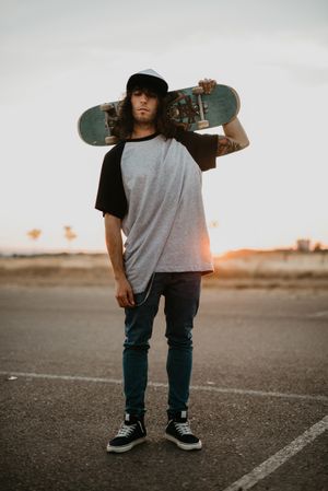 Cool confident man with skateboard looking at camera