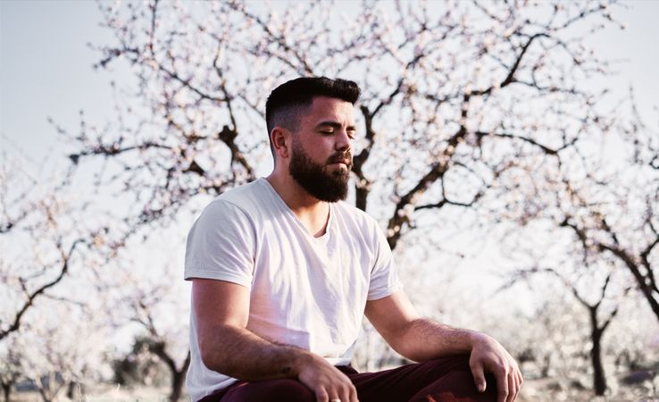 Bearded man meditating in spring garden