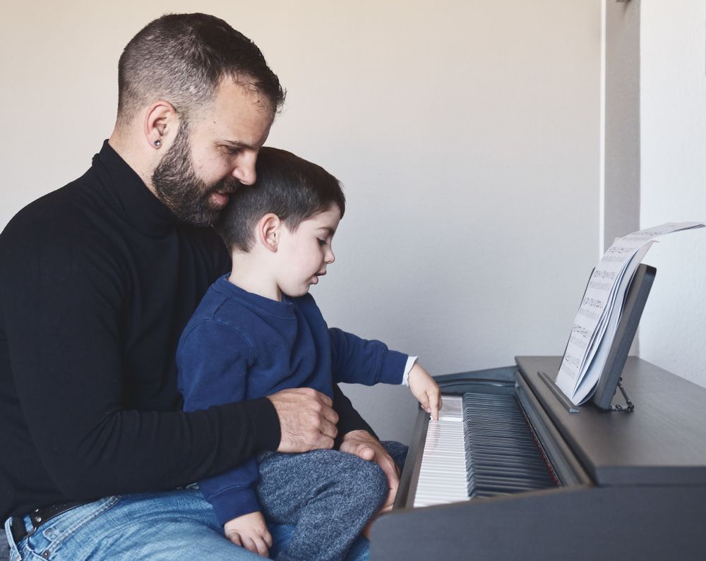 Father teaching son to play piano