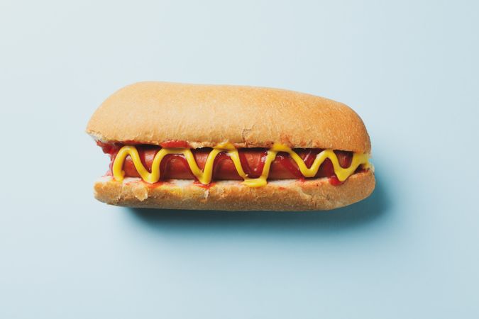 Tasty hot dog with sauces on blue background