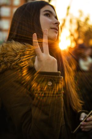 Young woman showing V sign on street