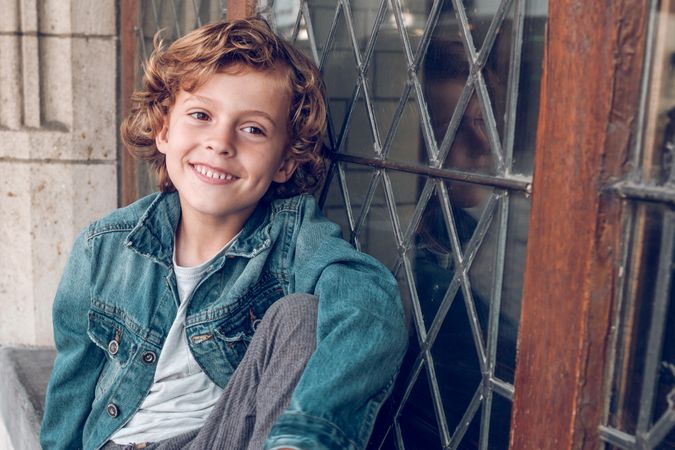 Cheerful boy sitting near old building
