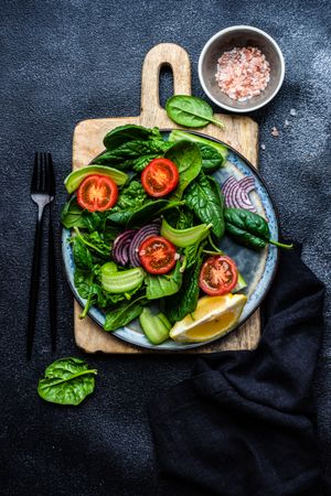 Top view of spinach salad with cherry tomatoes and red onions