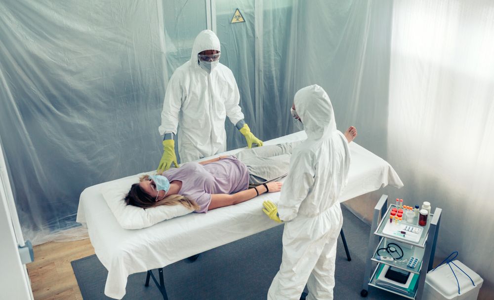 Doctors in bacteriological protection suit observing a patient lying on a gurney