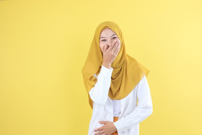 Happy Young Woman Giggling, Covering Mouth While Trying to Stop Laughing