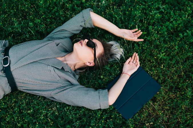 Woman with tablet in stylish suit lying in grass