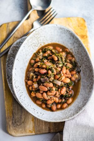 Top view of traditional Georgian bean dish - lobio, served in modern textured ceramic bowl on wooden board