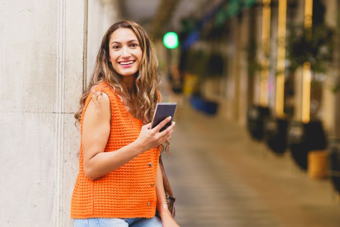 Woman leaning with phone on street outside