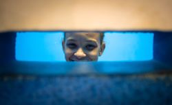 Rio de Janeiro, Brazil - February 13 2014: Cheerful kid looking at wall slit