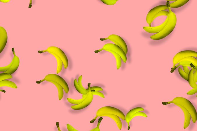 Scattered yellow bananas on a pink background
