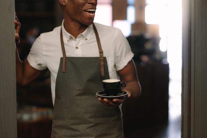 Cropped shot of barista standing at a café wearing apron
