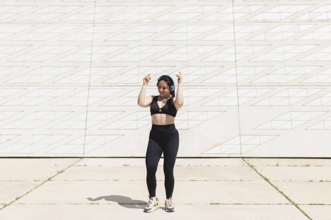 A young woman, dancing and moving, happy, while listening to music with headphones and disconnecting, to relax, after exercising