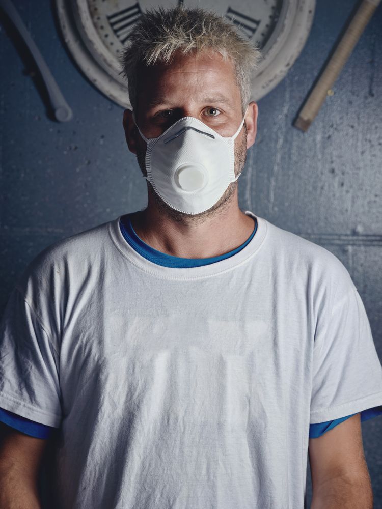 Blond surfboard maker with tattoos in mask