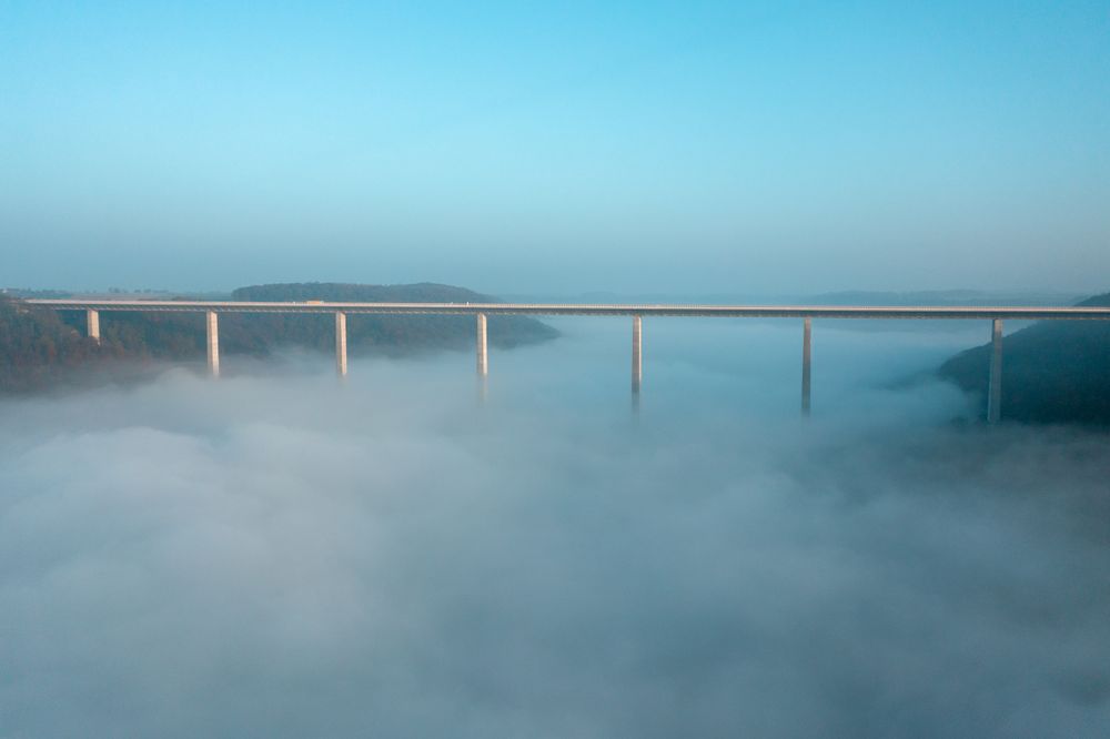 Germany's tallest bridge over dense fog, drone aerial view, at sunrise in Braunsbach, Germany