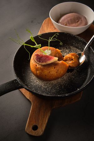 Pie served in frying pan with spoon on cutting board
