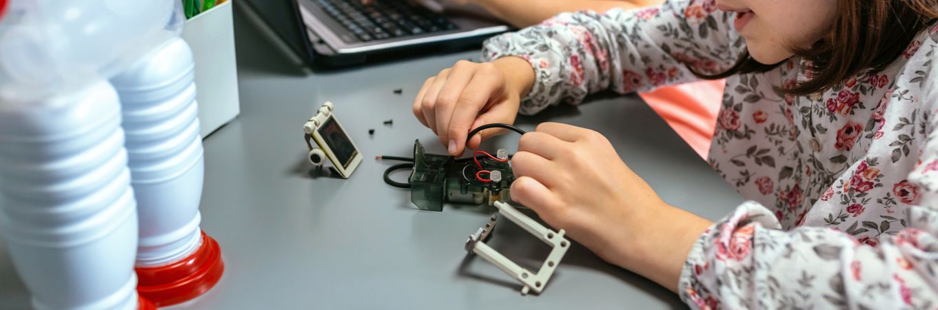 Female student connecting wire on electrical circuit in robotics class