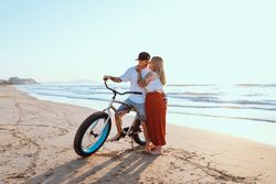 Peaceful couple kissing while standing on beach with bicycle